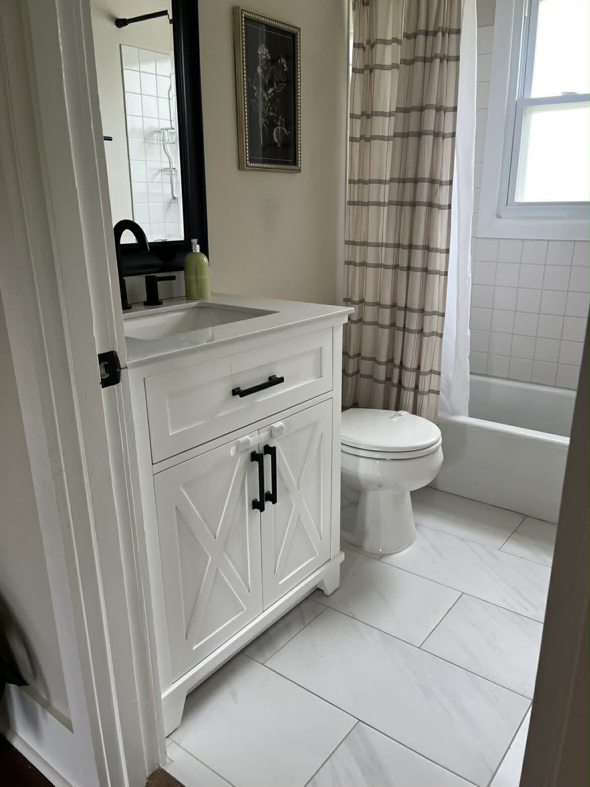 Clean white farmhouse bathroom with striped shower curtain