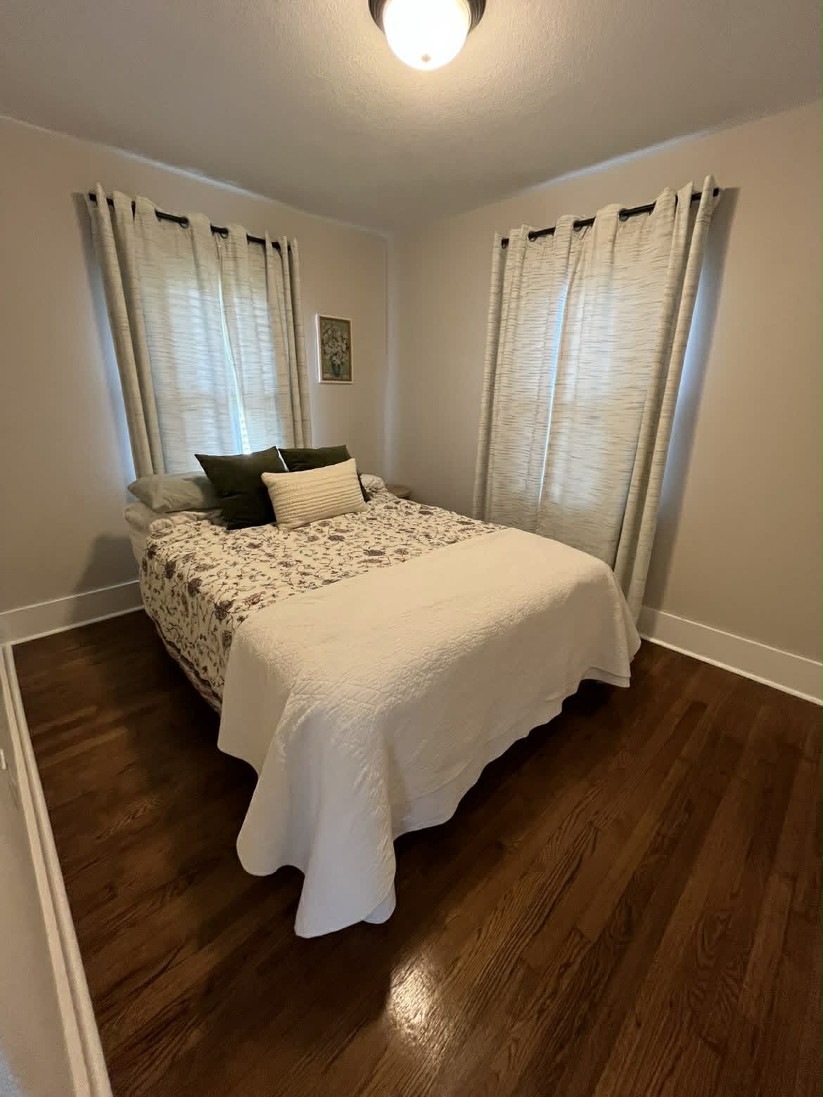 Clean small bedroom with white floral quilt