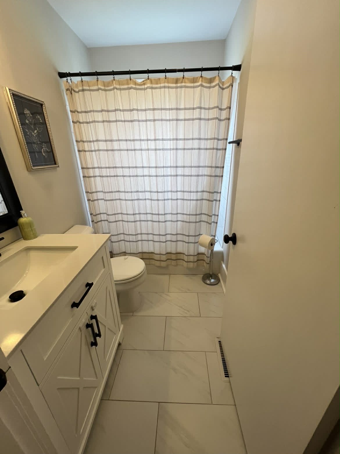 White bathroom doorway view with striped shower curtain