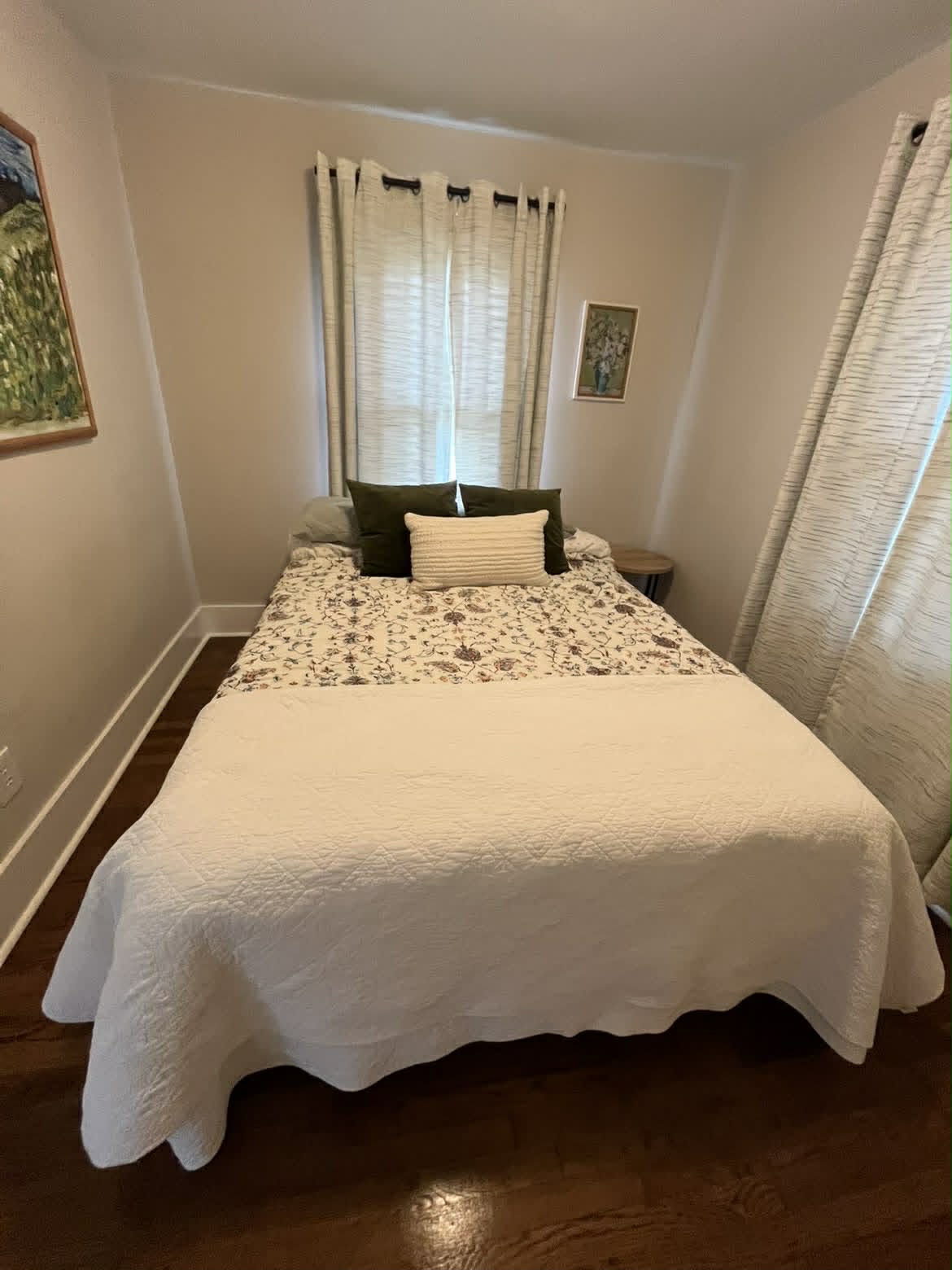 Clean small bedroom with white floral quilt and nightstand