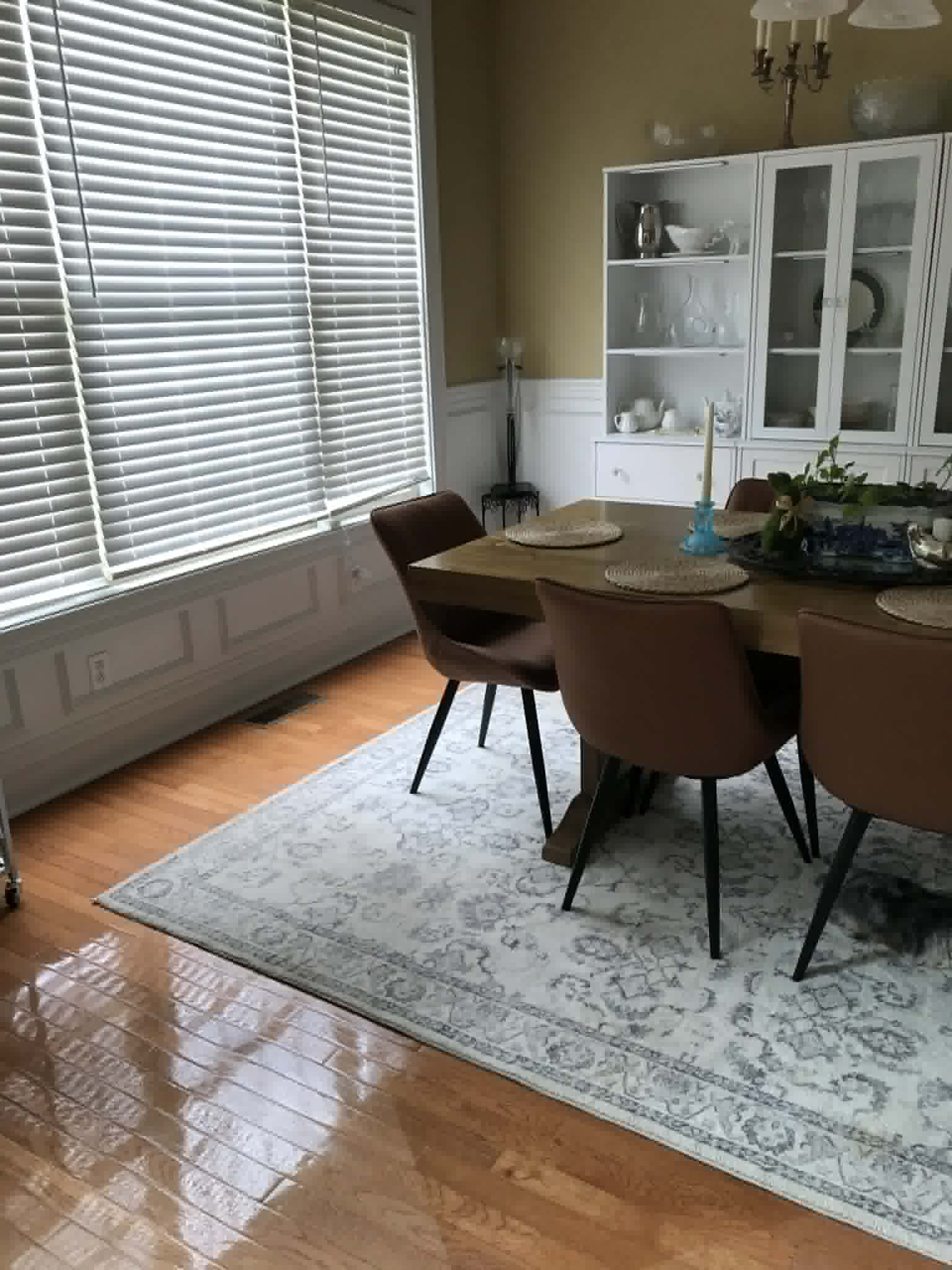 Clean dining room with white china cabinet and wainscoting